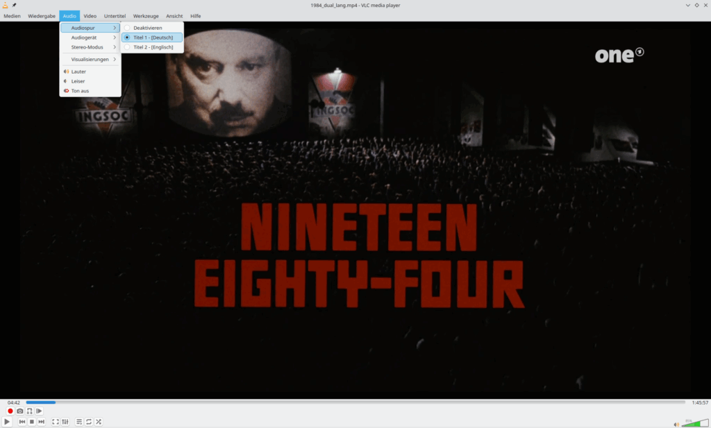 Der Videoplayer VLC zeigt die Titelsequenz des Films 1984, das Audiomenü mit der Audiospur-Auswahl ist geöffnet. Zur Auswahl stehen Deutsch und Englisch, Deutsch ist ausgewählt.